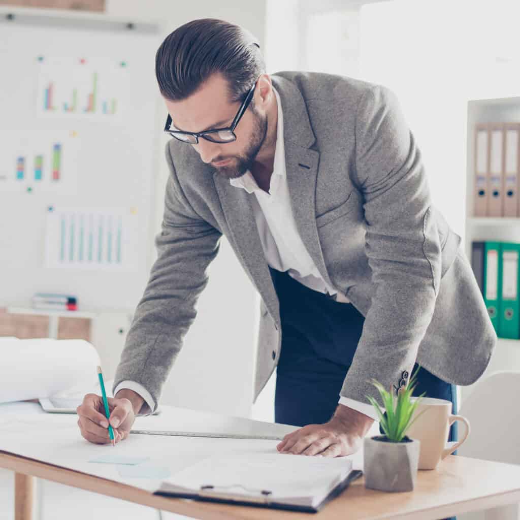 designer in formal wear and glasses draws a diagram on paper