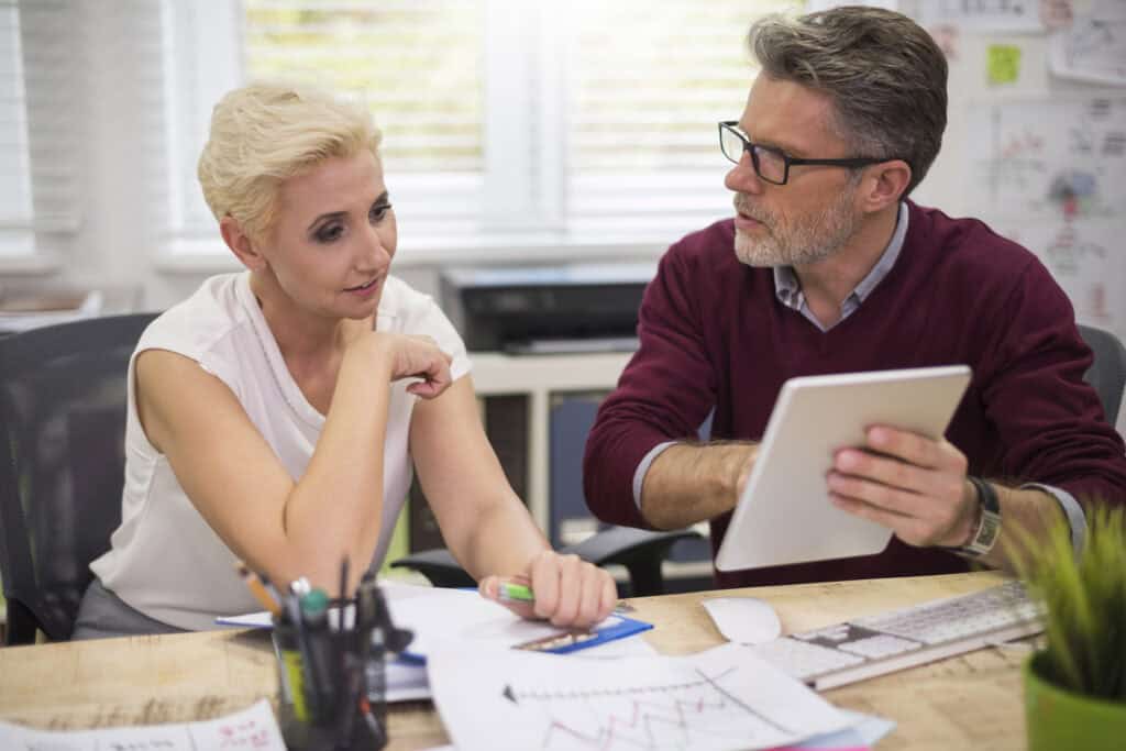 Woman and man working in finance management sit in office and discuss reports