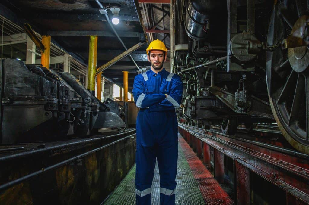 Field service automation professional in a blue safety outfit stands in a dark hall.