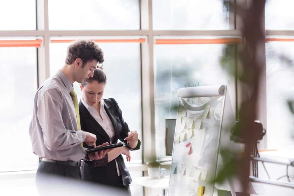 Man and woman brainstorming ideas together, using tablet and flipboard